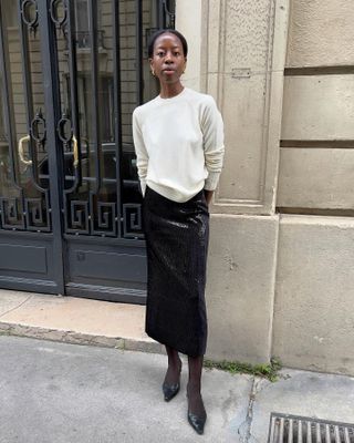 French woman wearing a sweater, sequin skirt, and tights.