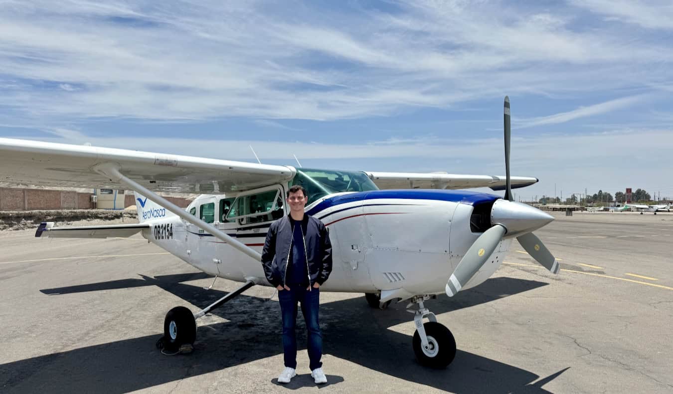 Nomadic Matt posing near a small airplane while traveling around Peru