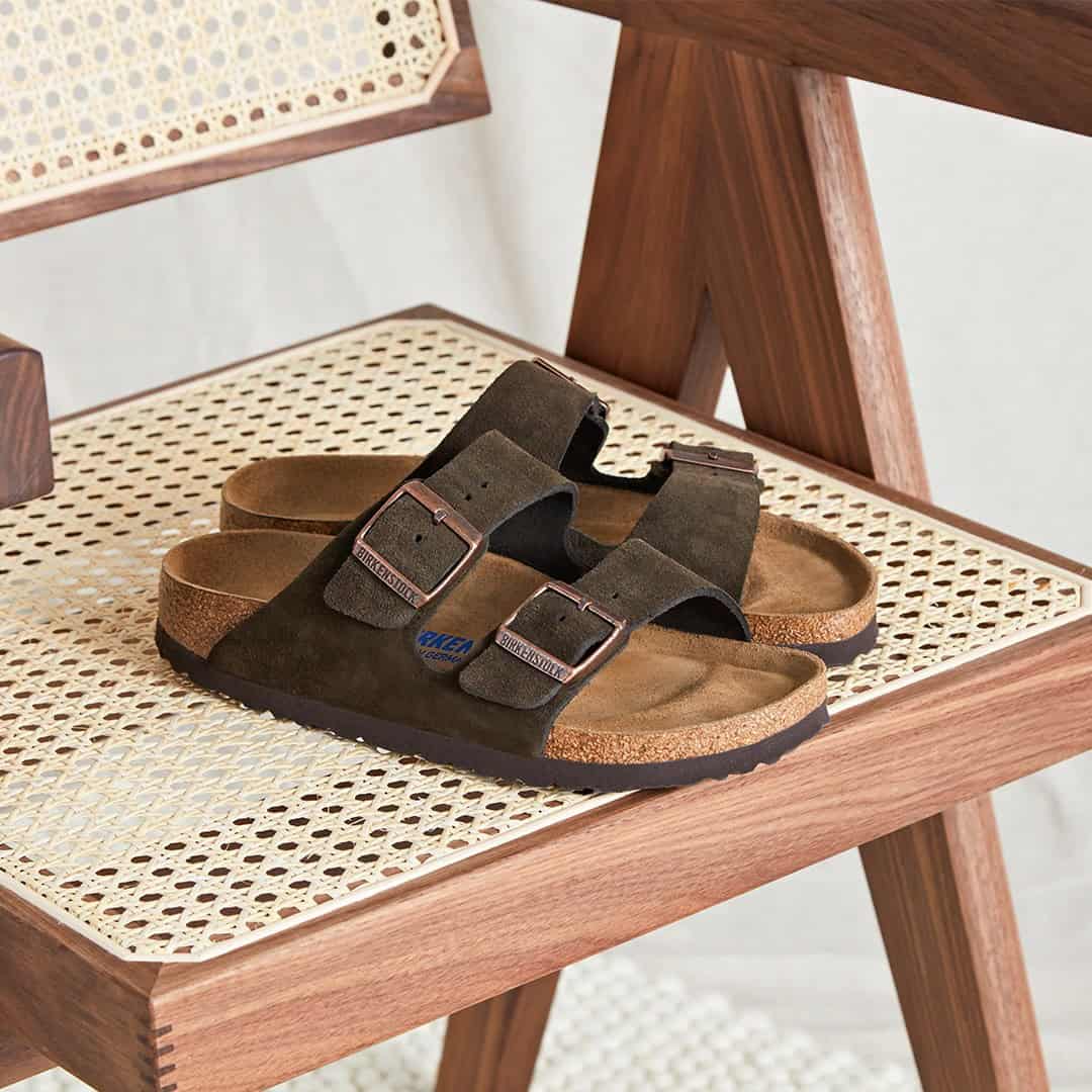 a pair of suede arizona sandals by birkenstock on a chair