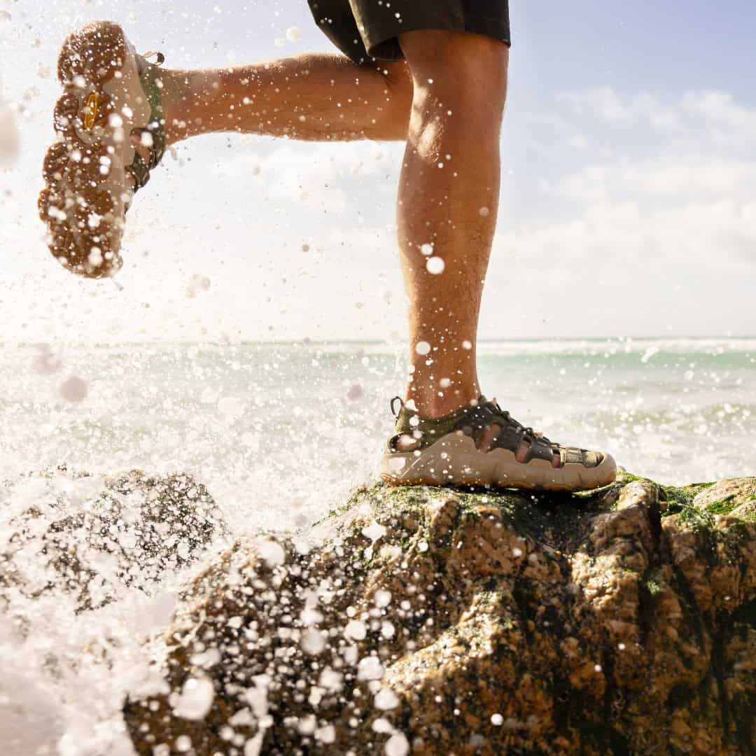 man jumping from rock to rock by the sea