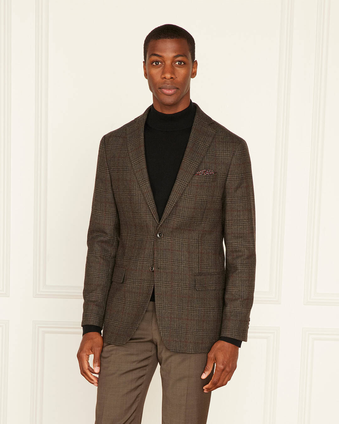 man wearing a brown checked blazer and pants with black turtle neck shirt