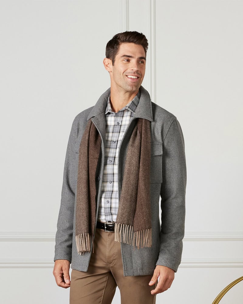 man wearing a gray jacket and brown scarf over a white checked shirt
