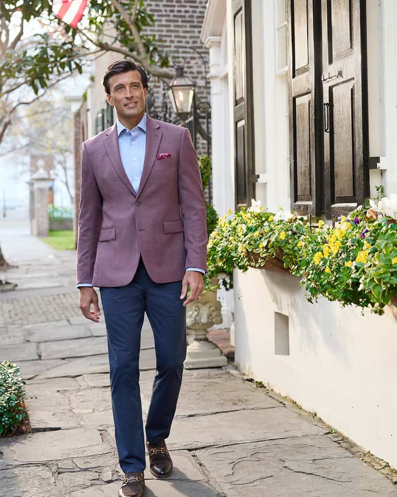 manwearingamaroonblazer paired with blue pants and horsebit loafers