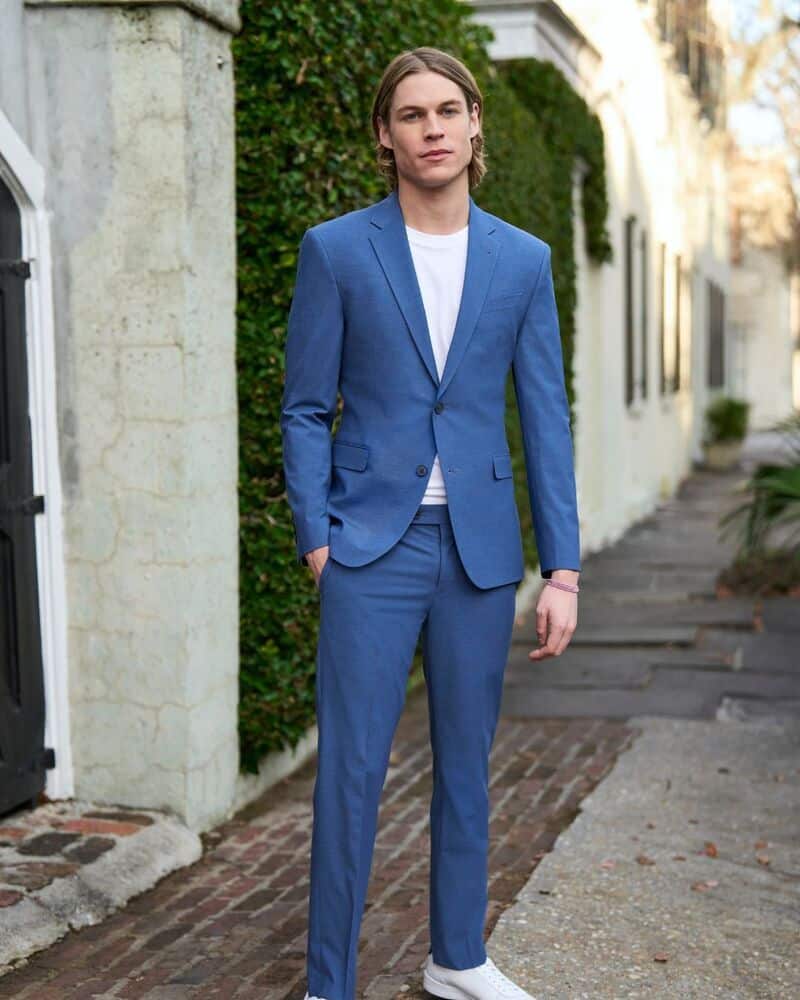 man wearing a two piece blue suit and white sneakers