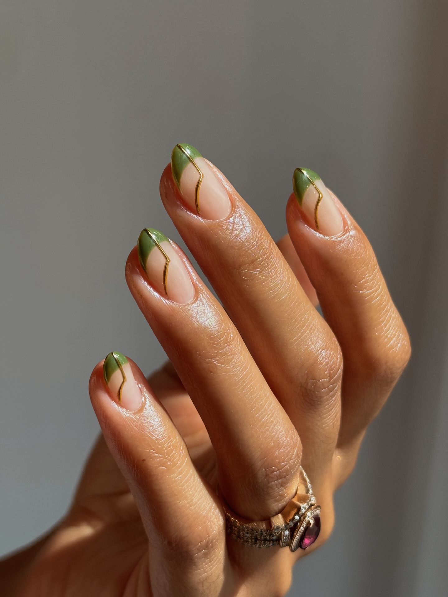 A manicure with green french tips and gold details by Queenie Nguyen